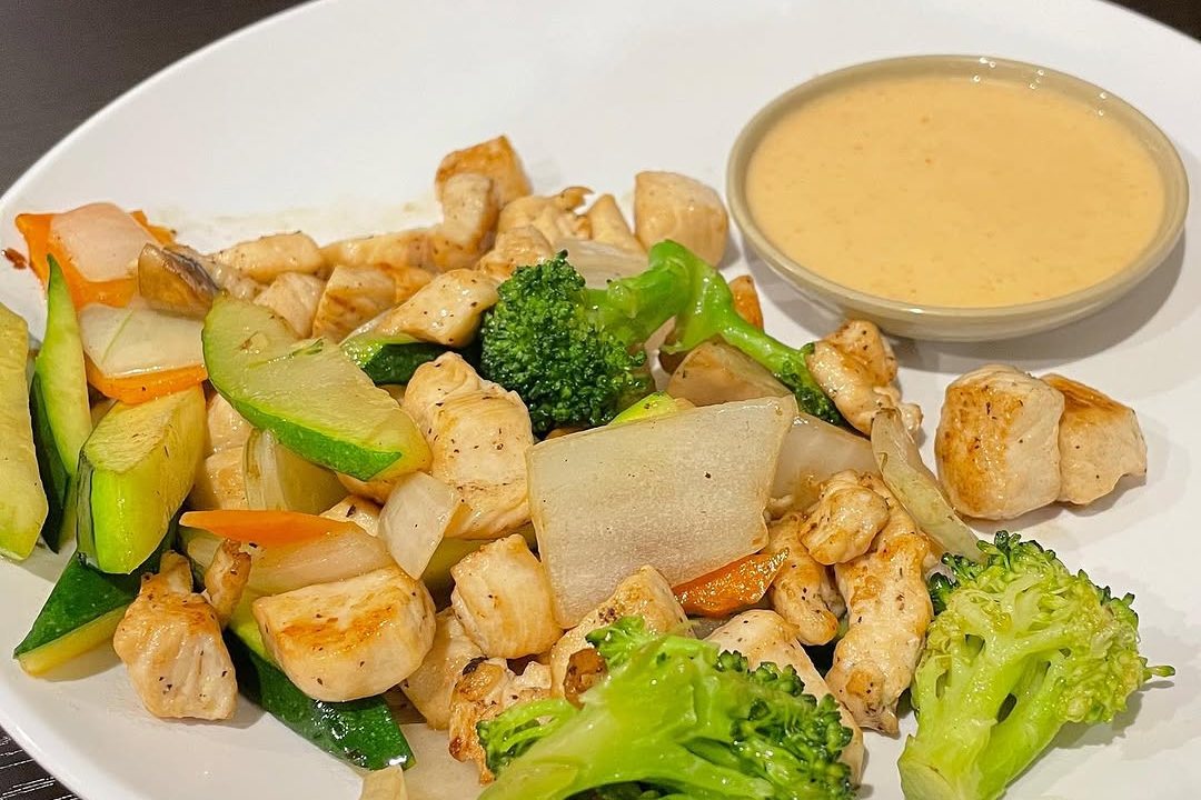 Hibachi chicken with broccoli, zucchini and onion on a white plate